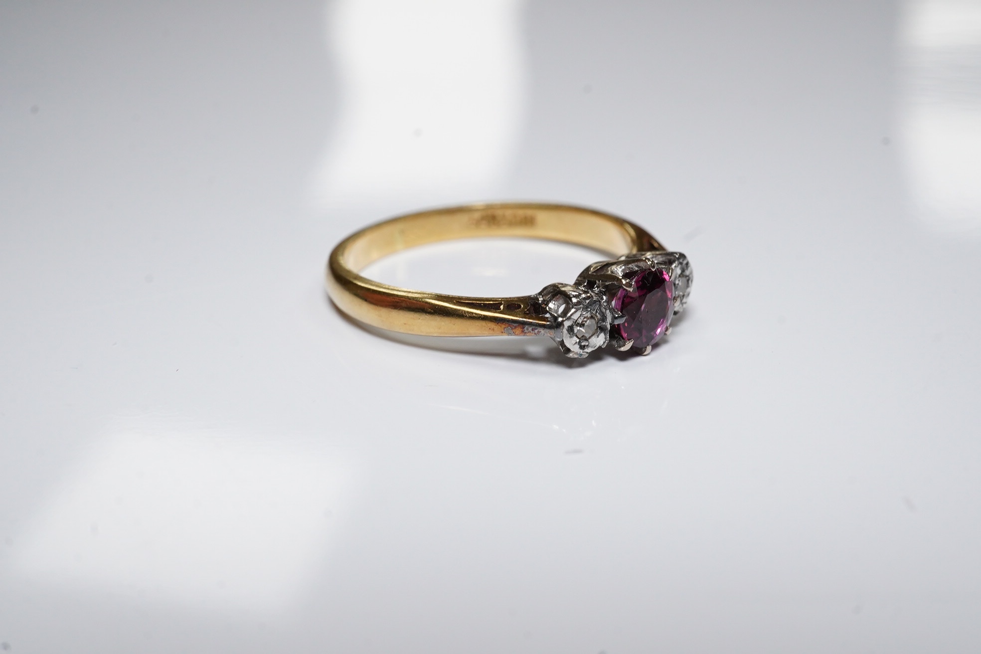 An 18ct and platinum ruby and diamond set three stone ring, size O, gross weight 3.1 grams. Condition - fair